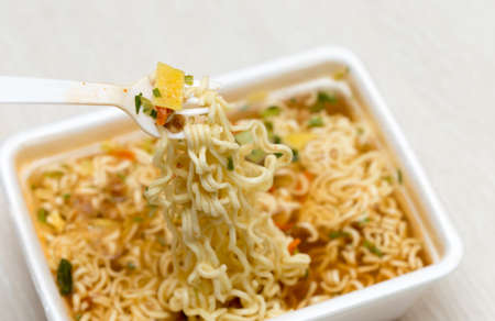 Raw food noodles quickly with a fork on the tableの写真素材