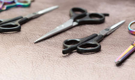 different barber scissors on a brown leather backgroundの写真素材
