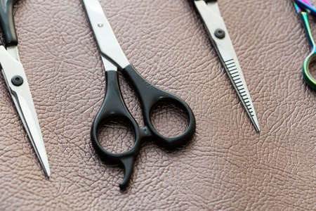 different barber scissors on a brown leather backgroundの写真素材