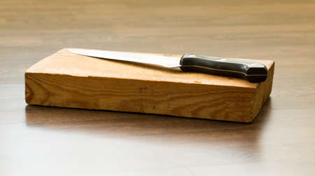 knife on wooden scratch cutting boardの写真素材