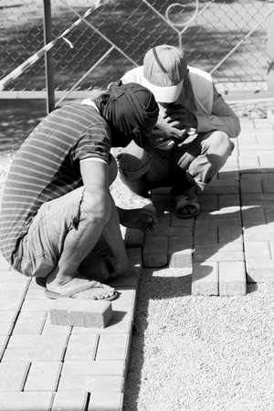 mason worker making sidewalk pavement with stone blocksの写真素材