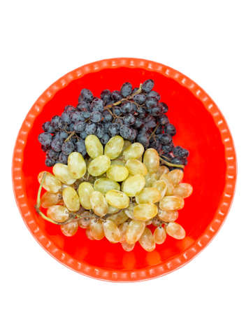 Two kind of grape black and yellow on a red plastic bowl isolated on white backgroundの写真素材