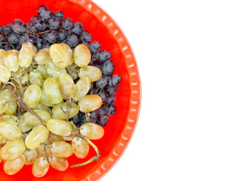 Two kind of grape black and yellow on a red plastic bowl isolated on white backgroundの写真素材