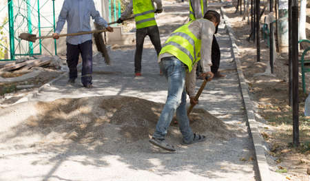 mason worker making sidewalk pavement with stone blocksの写真素材
