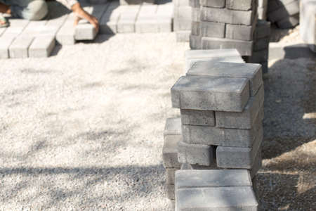 mason worker making sidewalk pavement with stone blocksの写真素材