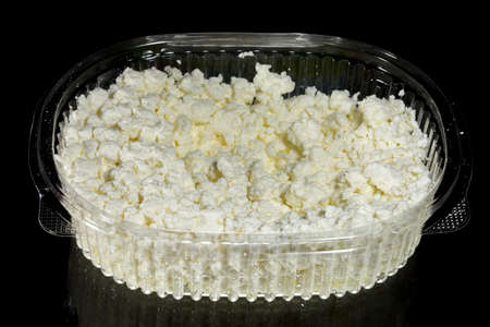 Low-fat cottage cheese in a one-time use plastic bowl with text space, isolated on a black backgroundの写真素材