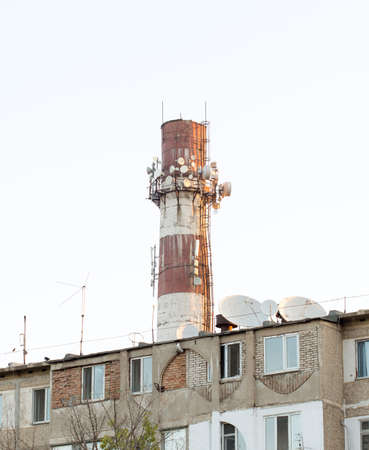 Brick flue with connected repeaters in an industrial area on the sky background