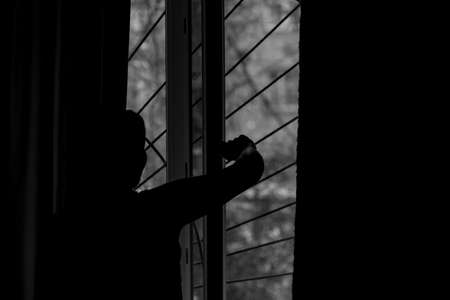 A young girl opens the curtains in the morning and relaxing. photo black and whiteの写真素材