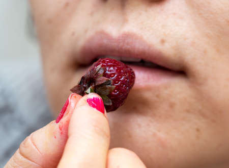 Girl eats strawberry macro