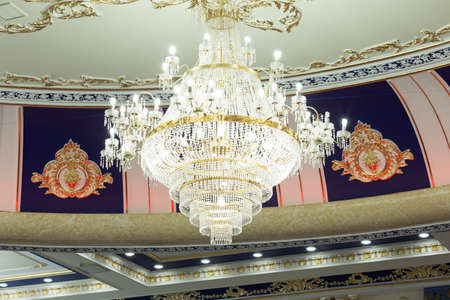 Beautiful crystal ancient chandelier in a hall. Lamp with soft yellow lightの写真素材