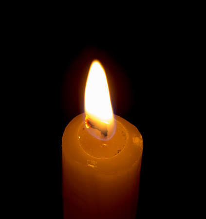 candle lit brightly against a black backgroundの写真素材