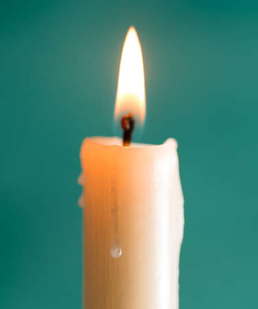 candle brightly lit on green backgroundの写真素材