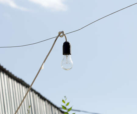 portrait vintage lamp hanging on a wire in the city, the blue sky and clouds in the background, selective focusの写真素材