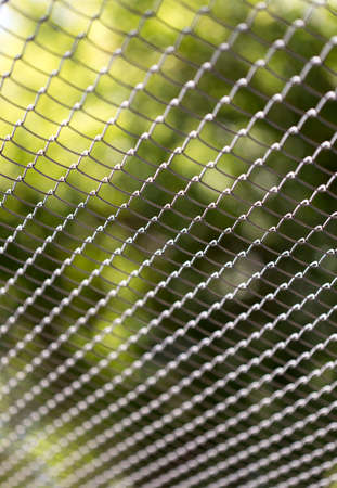 Green wire fence on background of green treesの写真素材