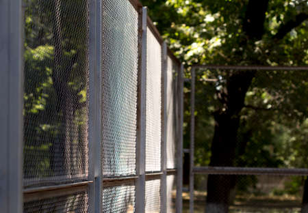 Green wire fence on background of green treesの写真素材