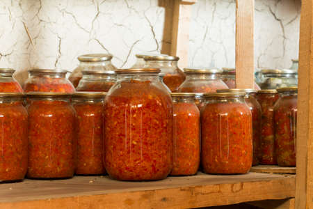 Preserved food in glass jars, on a wooden shelf. Various marinaded foodの写真素材
