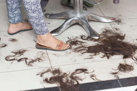 Dirty floor in the hairdresser's with hair. The master serves the customerの写真素材