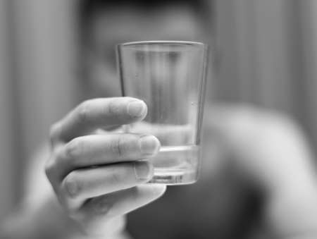 A young guy drinks water from a glassの写真素材