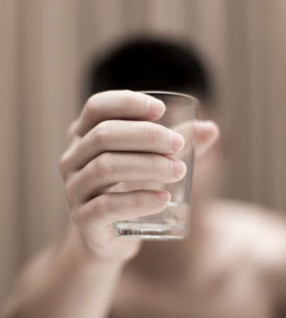 A young guy drinks water from a glassの写真素材