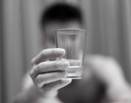 A young guy drinks water from a glassの写真素材