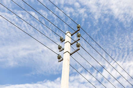 Pole with electric wires against the blue sky with clouds