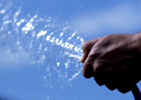 Man's hand with watering from the hoseの写真素材
