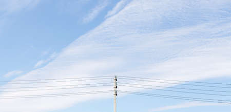Pole with electric wires against the blue sky with cloudsの写真素材