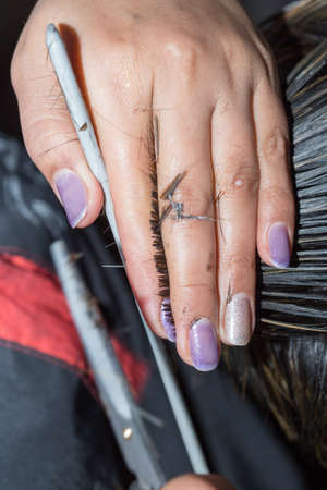 Closeup macro shot image of hairstylist hairdresser cutting customer woman hair in salon with scissors and comb, look from behind back sideの写真素材