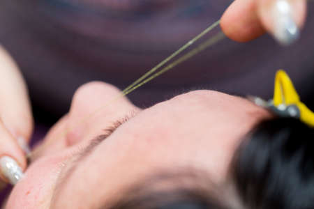Closeup shot of a woman in a nail salon receiving a manicure by a beautician with nail file. Woman getting nail manicure. Beautician file nails to a customer.の写真素材