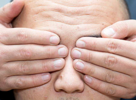 Man closes his eyes with his hand close-up