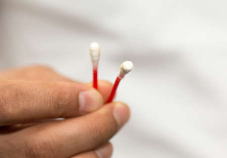 in the hands of a cotton swab and it is dirty, white backgroundの写真素材