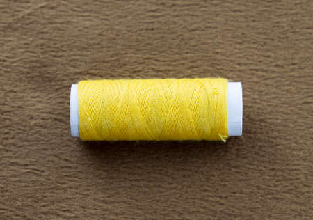 yellow bobbin on a background of brown cloth