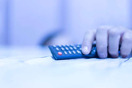 the man put his hand on the table using the TV remote controlの写真素材