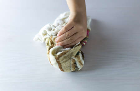 a child with a damp rag wipes the surface of the tableの写真素材