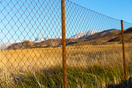 metal fence in the field at sunsetの写真素材