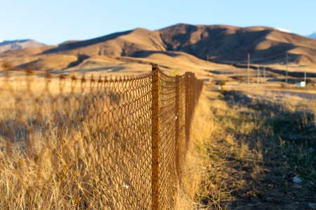 metal fence in the field at sunsetの写真素材