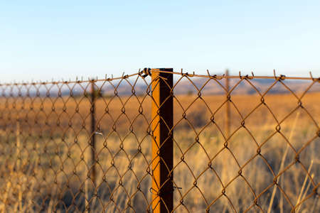 metal fence in the field at sunsetの写真素材