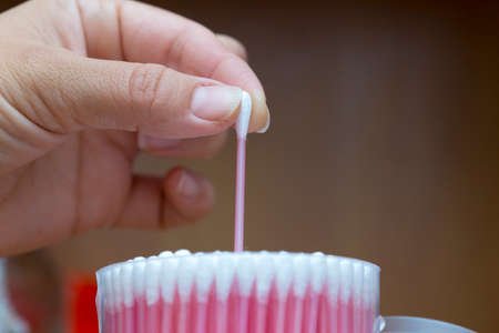 Hand pulls a cotton wand out of the box, a macro