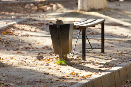a bench and a trash can in the parkの写真素材