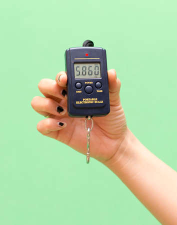 In the hand of a digital balance on a green backgroundの写真素材