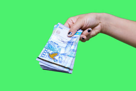 Kazakhstan money tens of thousands of banknotes in the hands of a girl, isolated on a green...
