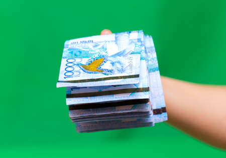 Kazakhstan money tens of thousands of banknotes in the hands of a girl, isolated on a green backgroundの写真素材