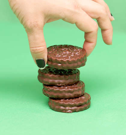 chocolate cookies on a green background in a woman's handの写真素材
