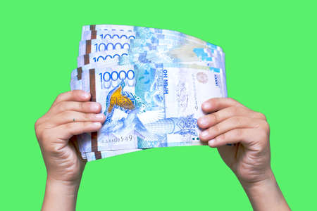 Kazakhstan money tens of thousands of banknotes in the hands of a girl, isolated on a green...