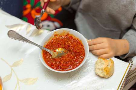 the child is eating a salad of tomatoes and bell peppersの写真素材