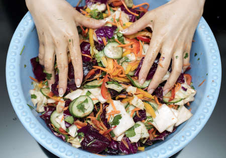 woman preparing salad with fresh vegetables. Preparation of tasty and healthy food on a black backgroundの写真素材