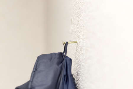 the jacket hangs on the screws on the wallの写真素材