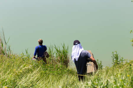 Fishermen go down to the river to find a good place for fishingの写真素材