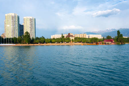 View of the skyscrapers and the mountains from Lake Sairan in the city of Almatyの写真素材