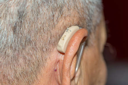 Digital modern hearing aid in the ear of aged old man